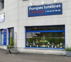 Devanture et vitrine des Pompes Funèbres Les Lys exposant des arrangements floraux