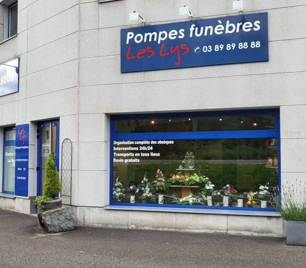 Devanture et vitrine des Pompes Funèbres Les Lys exposant des arrangements floraux