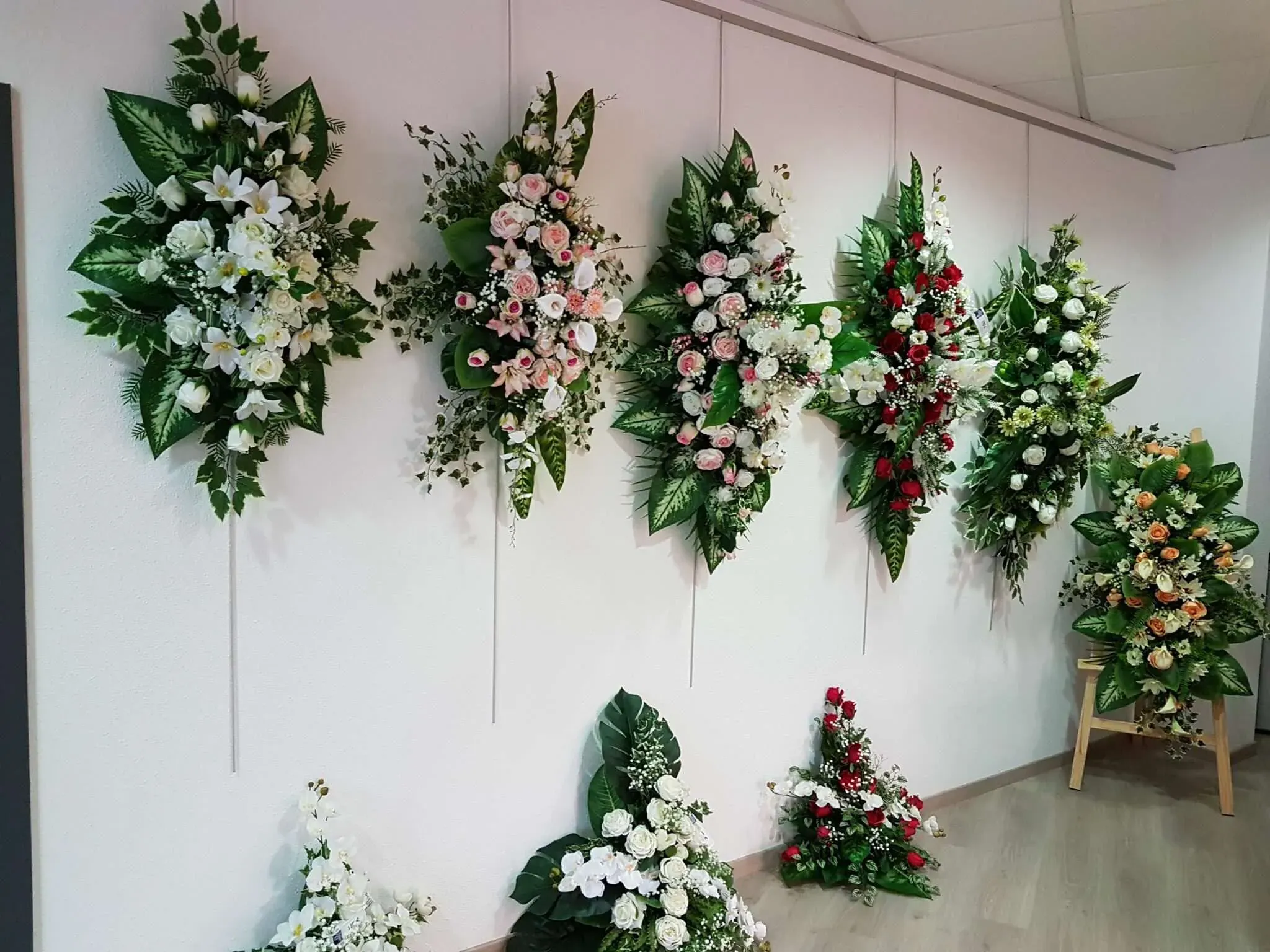 Exposition murale d'une variété de raquettes et compositions de fleurs de deuil