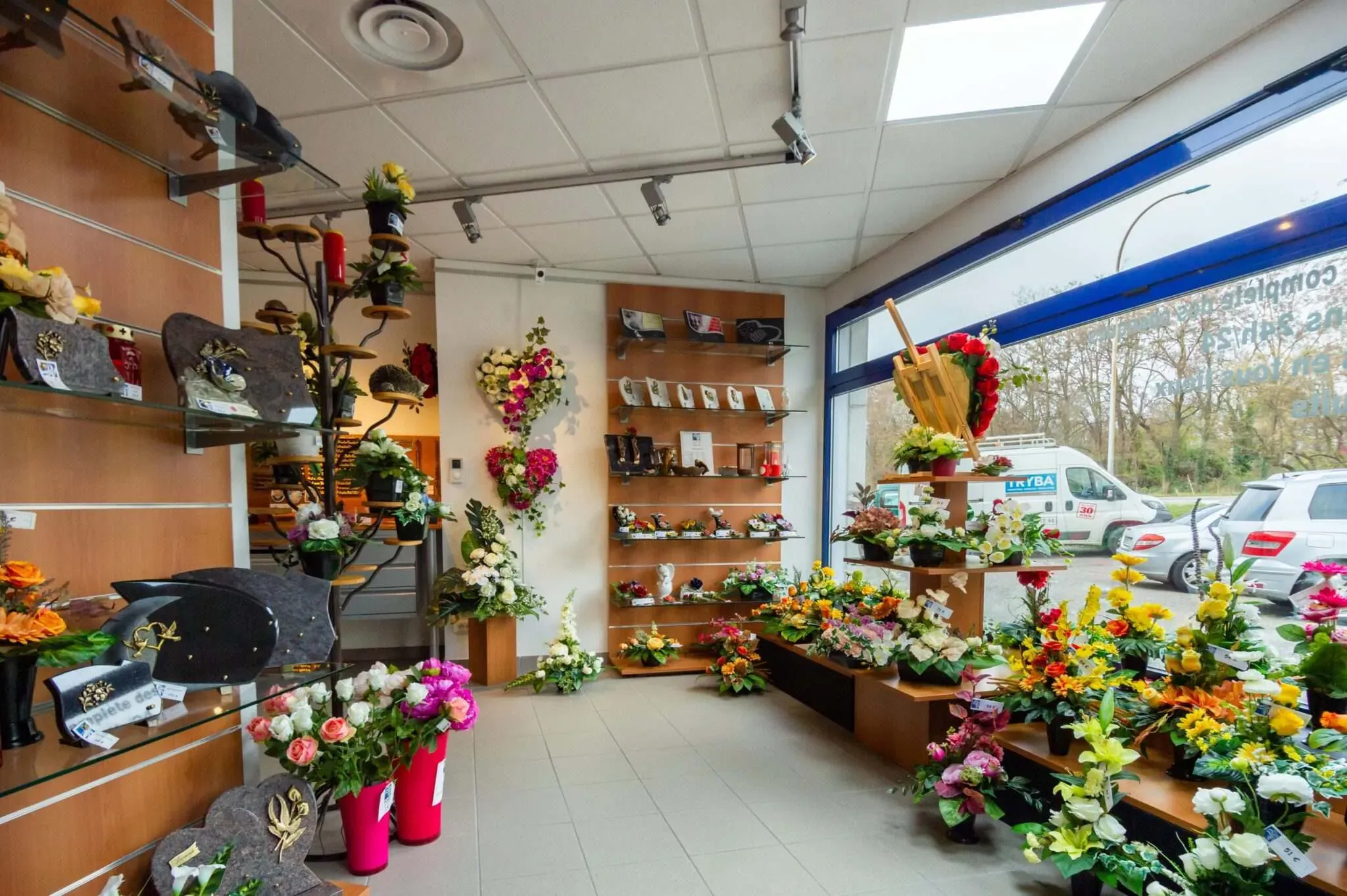 Intérieur de la boutique présentant des plaques funéraires et un large choix de fleurs de souvenir