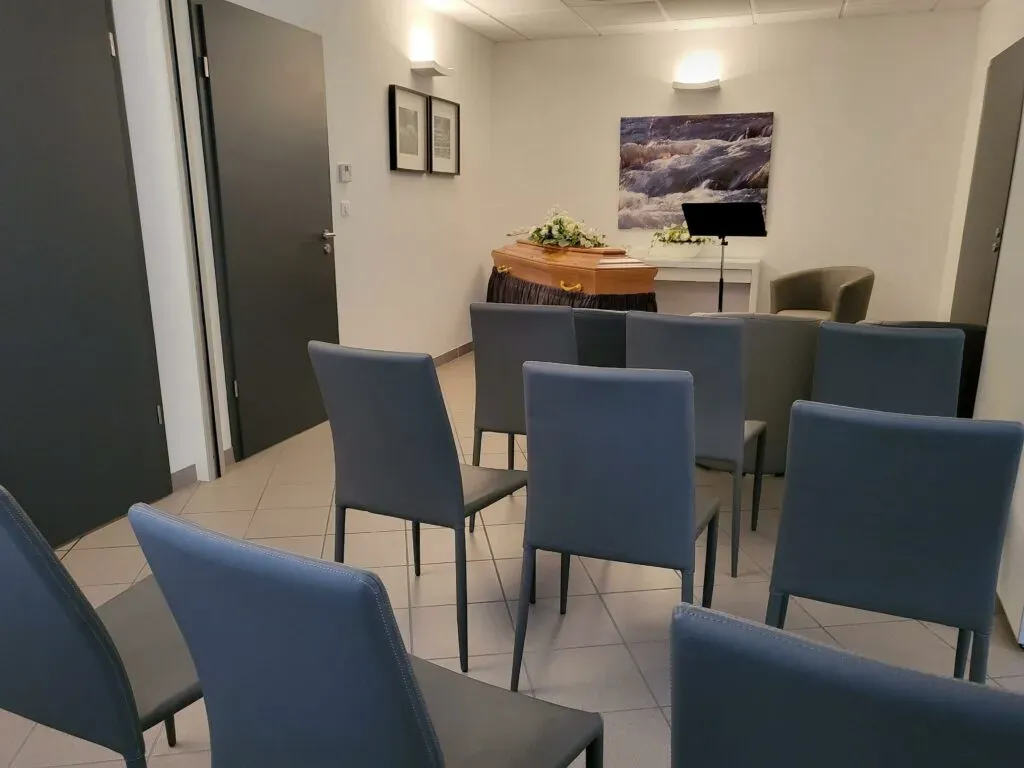 Salle de cérémonie funéraire agencée avec des chaises bleues modernes pour les familles